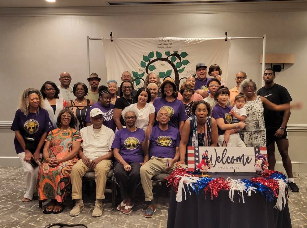 Spencer family elders and relatives gathered under the family tree banner
